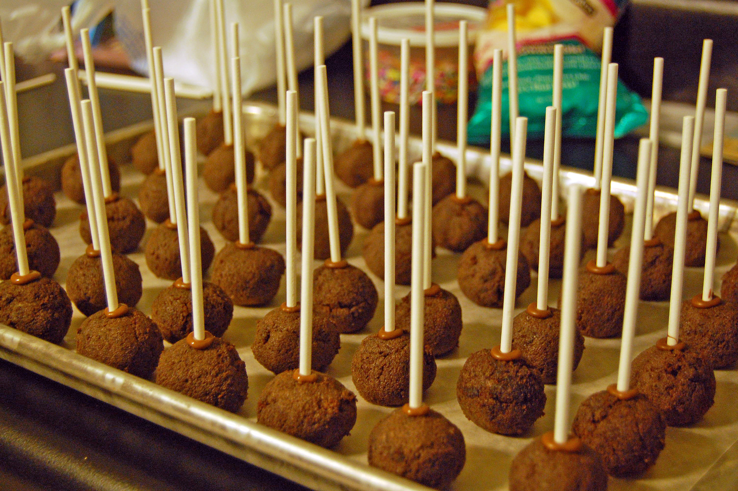 Cake balls with sticks on cookie sheet